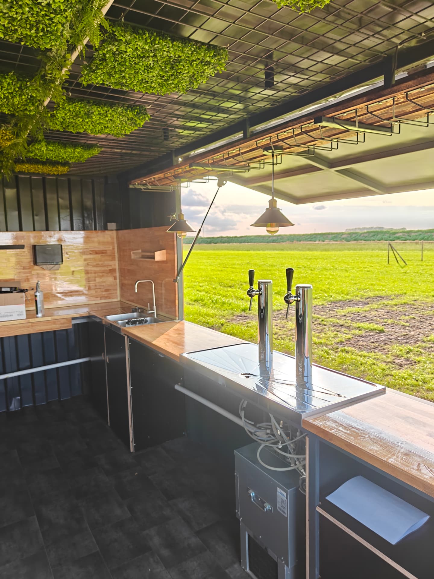 Binnenzicht met tapinstallatie, spoelbak en uitzicht op het veld