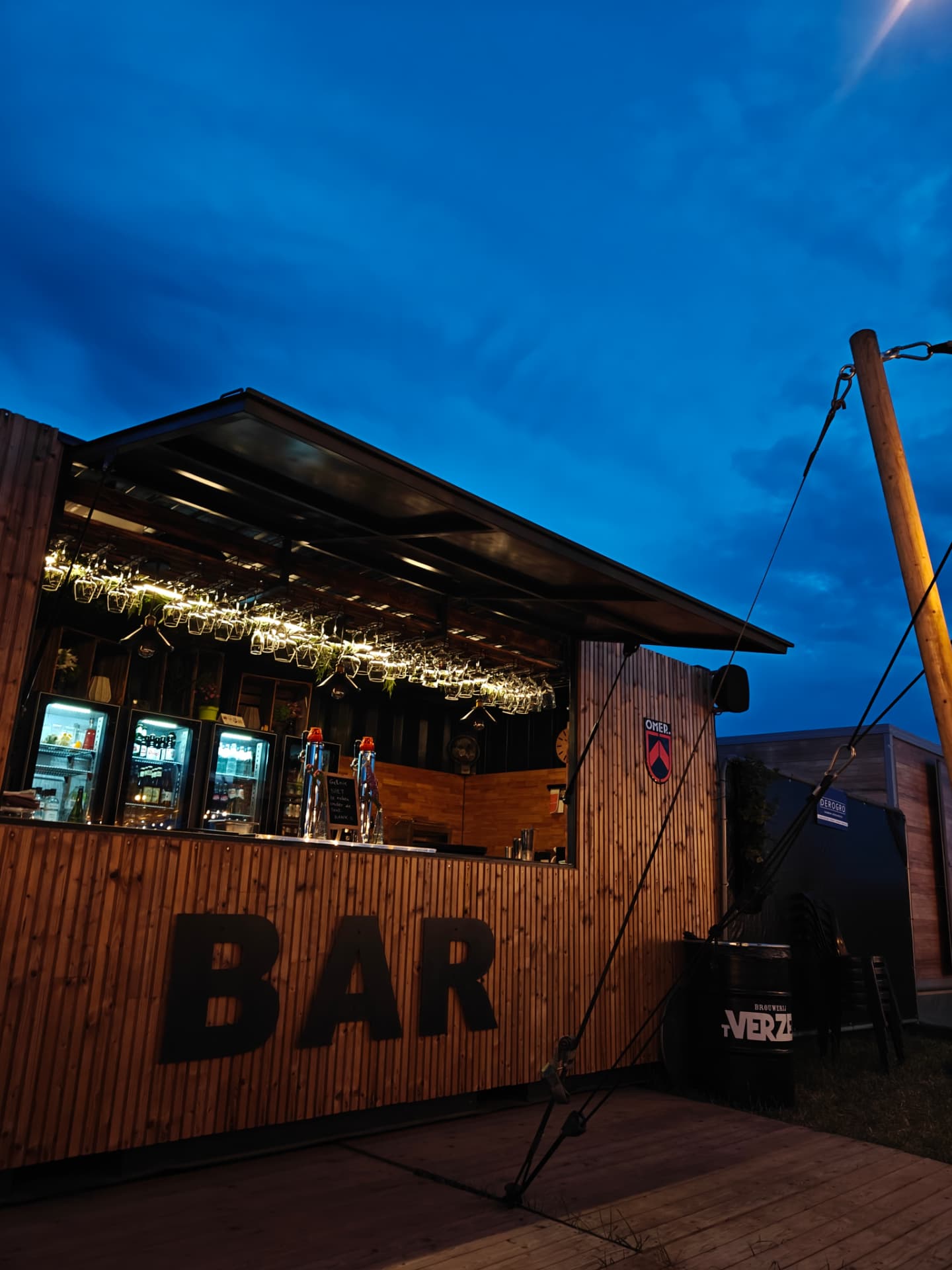 De barcontainer in de avond, verlicht onder een blauwe schemerhemel