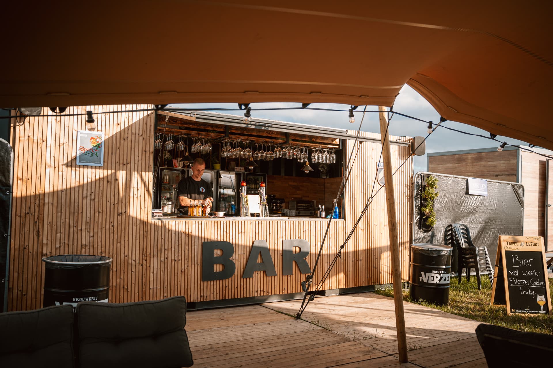 De barcontainer met loungezetels en tent op een evenement