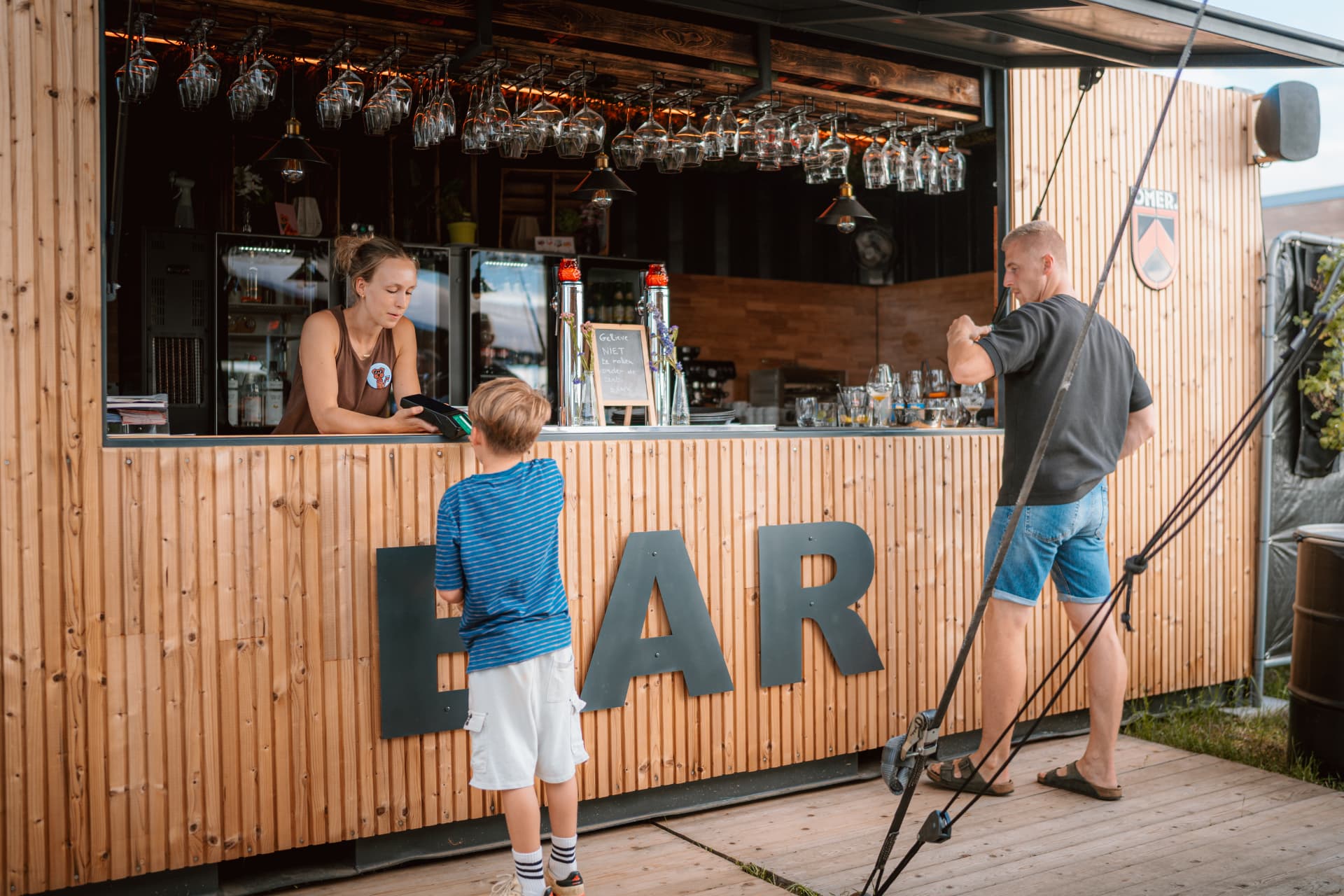 Gasten worden bediend aan de toog van de barcontainer